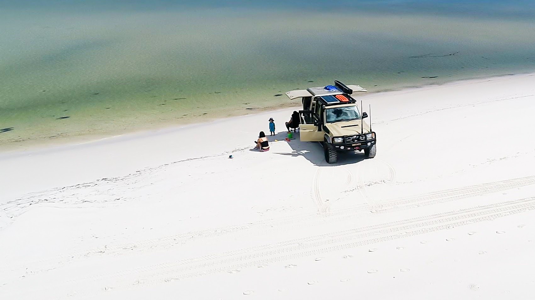 Jonathan's LandCruiser 79 touring rig, rooftop tent up, parked alone on a white-sand Australian beach.